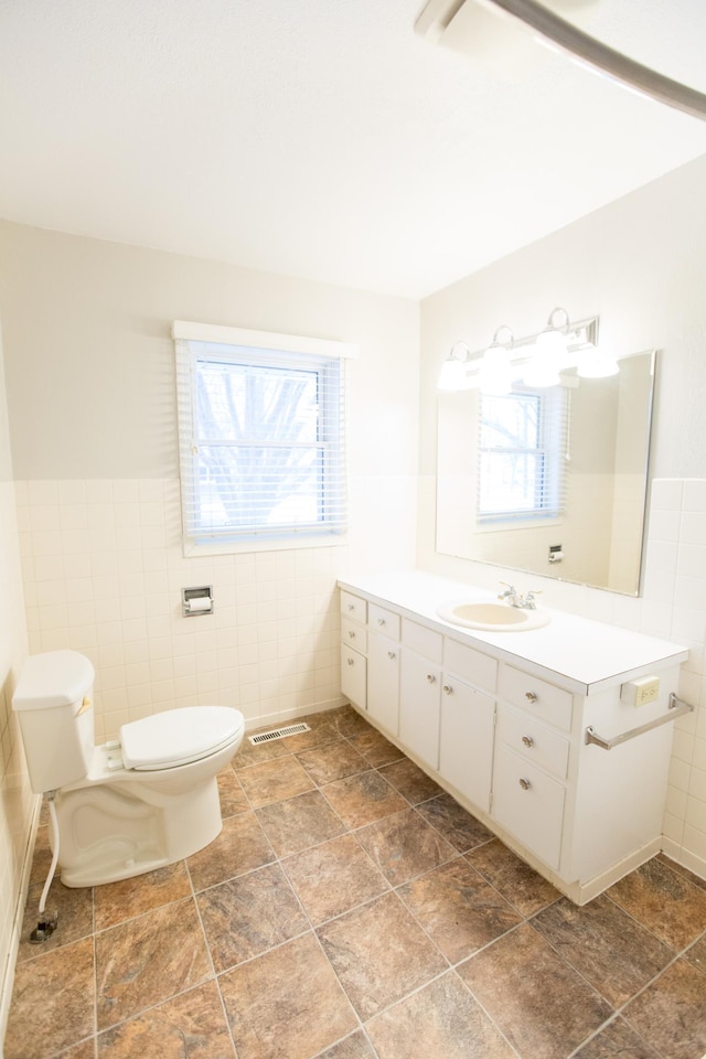 707 Haarfager Ave N, Canby, MN 56220 - bathroom featuring tile walls, toilet, plenty of natural light, vanity, and a wainscoted wall
