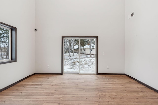 spare room featuring a high ceiling and light hardwood / wood-style flooring