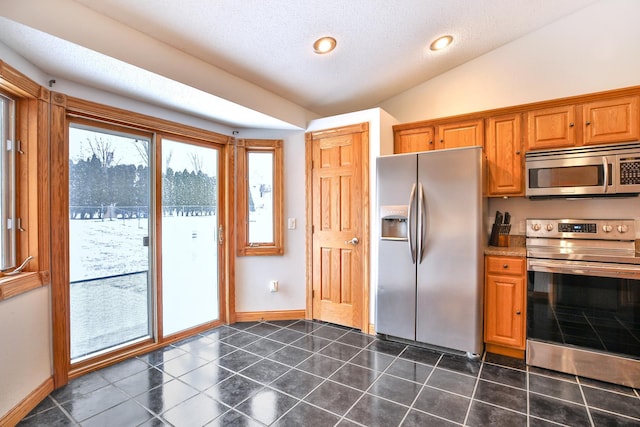 kitchen with a textured ceiling, lofted ceiling, and appliances with stainless steel finishes