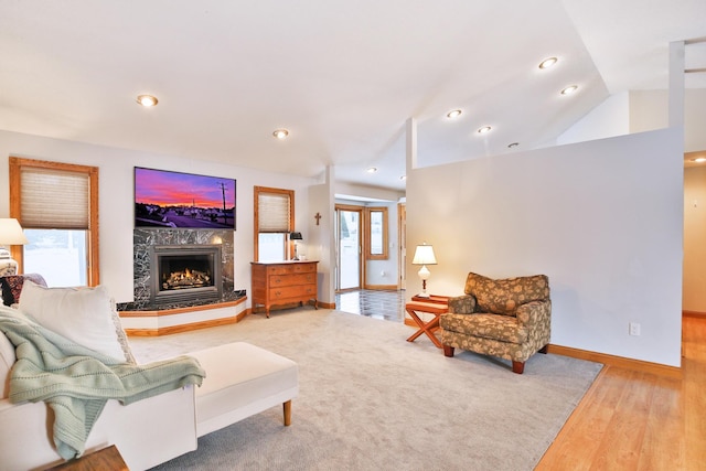 living room with hardwood / wood-style flooring, lofted ceiling, and a premium fireplace