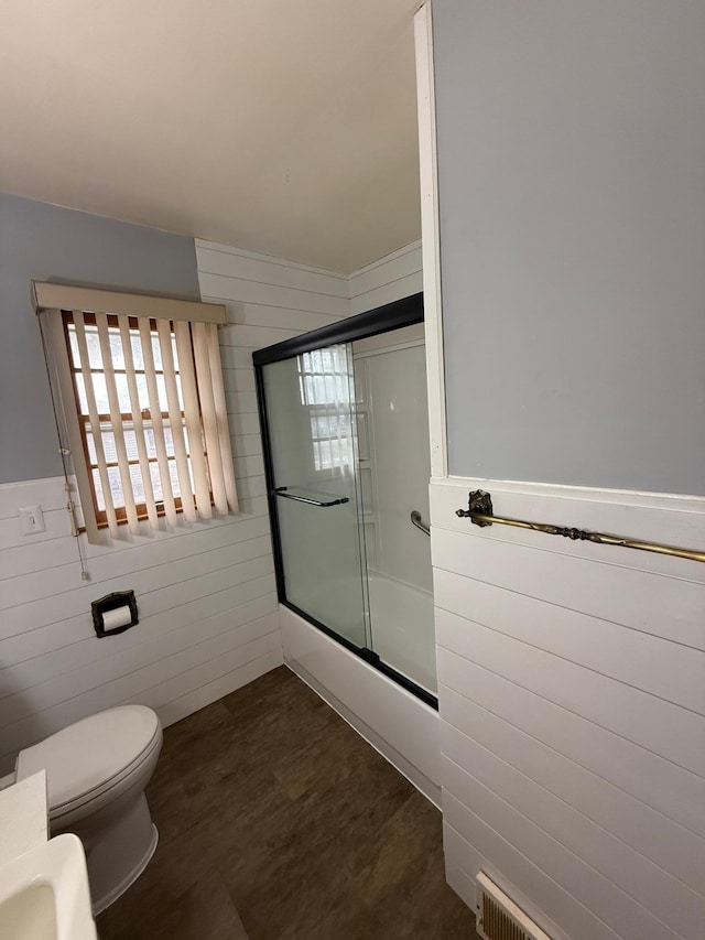 bathroom featuring enclosed tub / shower combo and toilet