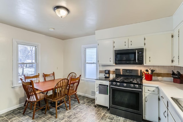 kitchen with sink, backsplash, white cabinetry, and stainless steel gas range