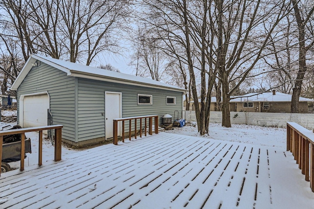 snow covered deck with an outbuilding and a garage