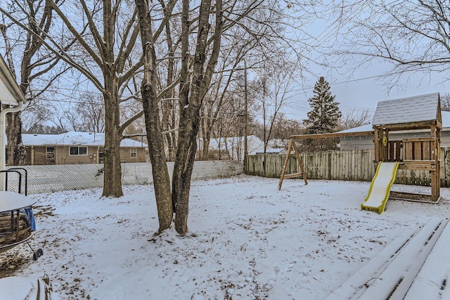 yard covered in snow featuring a playground