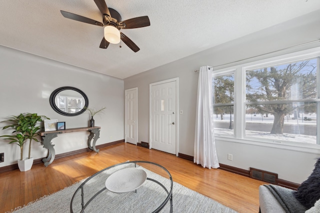 interior space featuring ceiling fan, a textured ceiling, and light hardwood / wood-style flooring