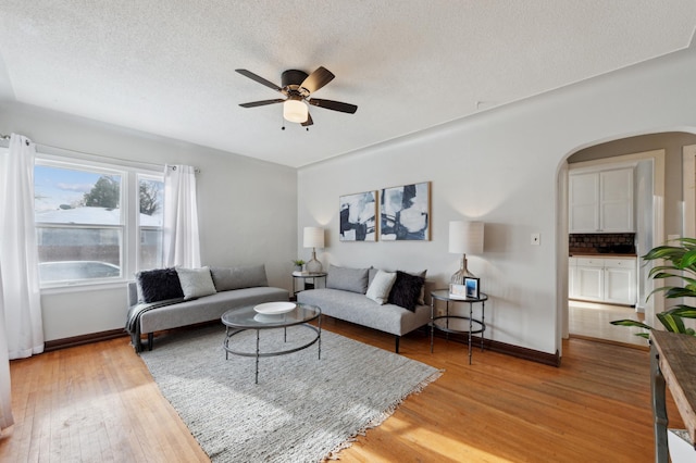 living room featuring ceiling fan, wood-type flooring, and a textured ceiling