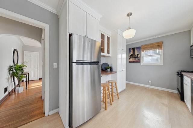 kitchen with white cabinetry, light hardwood / wood-style floors, stainless steel appliances, ornamental molding, and pendant lighting