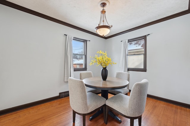 dining area with a textured ceiling, crown molding, and hardwood / wood-style floors