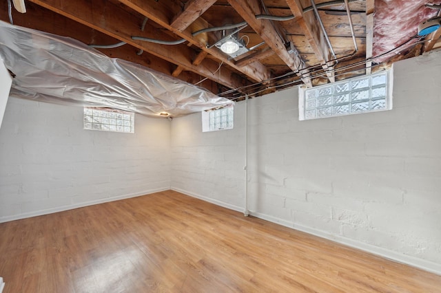 basement featuring brick wall and hardwood / wood-style flooring