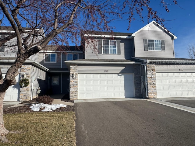 traditional-style house with stone siding, aphalt driveway, and an attached garage