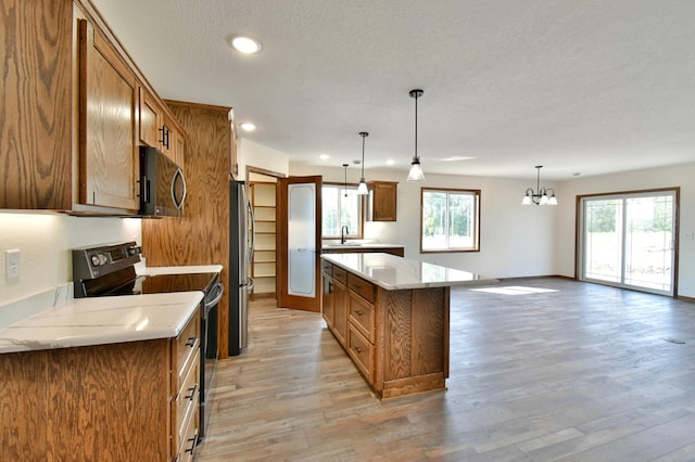 kitchen featuring stainless steel fridge, stove, pendant lighting, an inviting chandelier, and a large island