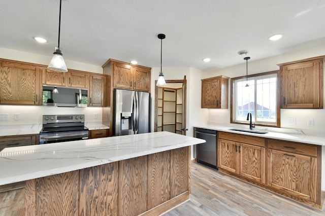 kitchen featuring stainless steel appliances, hanging light fixtures, light hardwood / wood-style floors, and sink