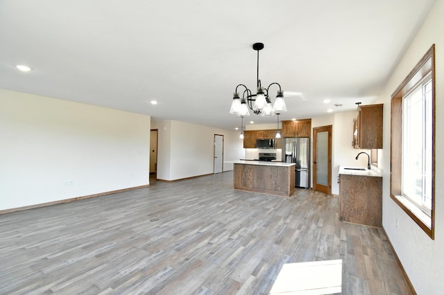 kitchen with sink, an inviting chandelier, stainless steel fridge with ice dispenser, light hardwood / wood-style flooring, and decorative light fixtures