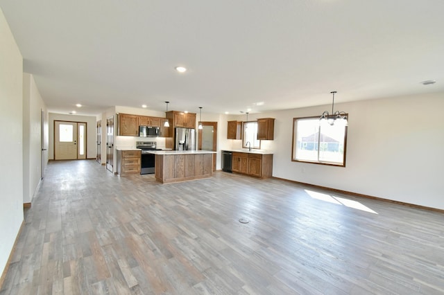 kitchen featuring decorative light fixtures, a center island, plenty of natural light, and stainless steel appliances