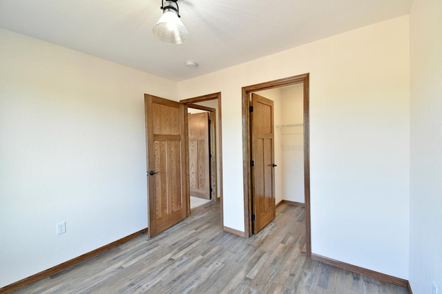 unfurnished bedroom with light hardwood / wood-style floors, a spacious closet, and a closet