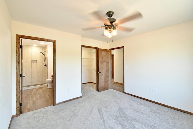 unfurnished bedroom with a walk in closet, light colored carpet, ceiling fan, connected bathroom, and a closet