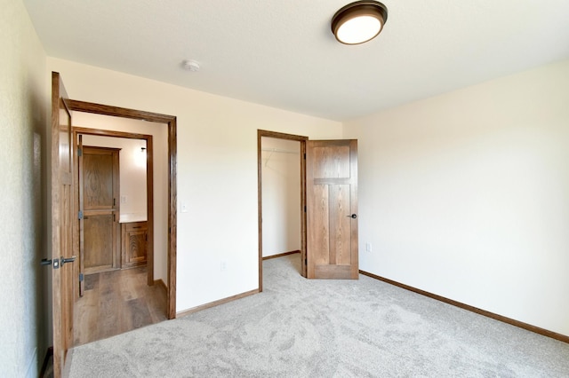 unfurnished bedroom with a walk in closet, a closet, and light colored carpet