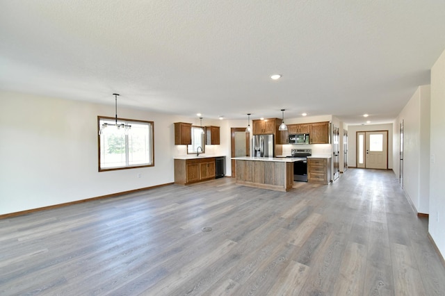 kitchen featuring sink, stainless steel appliances, hardwood / wood-style floors, decorative light fixtures, and a kitchen island