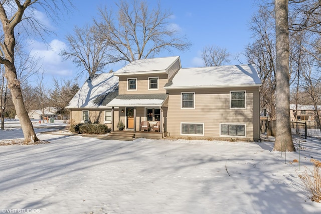 snow covered back of property featuring a porch