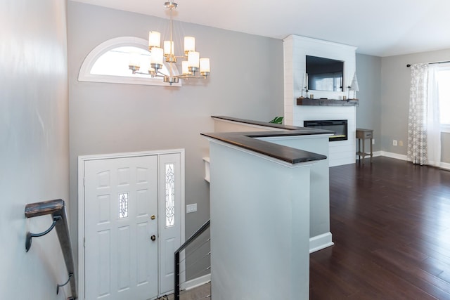 foyer featuring a large fireplace, dark hardwood / wood-style flooring, and a chandelier