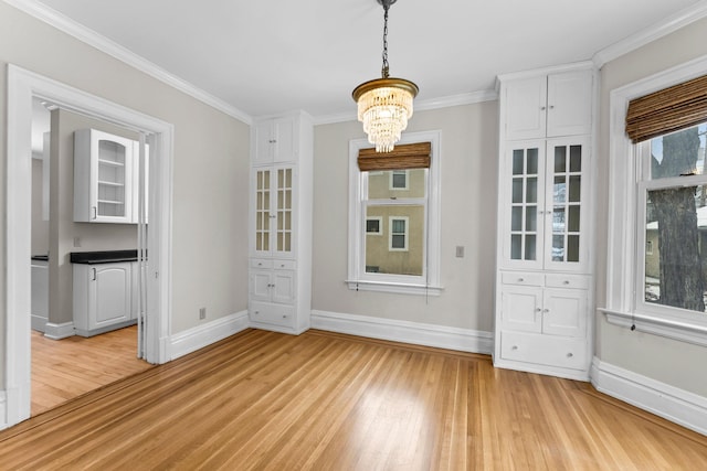 unfurnished dining area featuring a notable chandelier, light hardwood / wood-style flooring, plenty of natural light, and crown molding