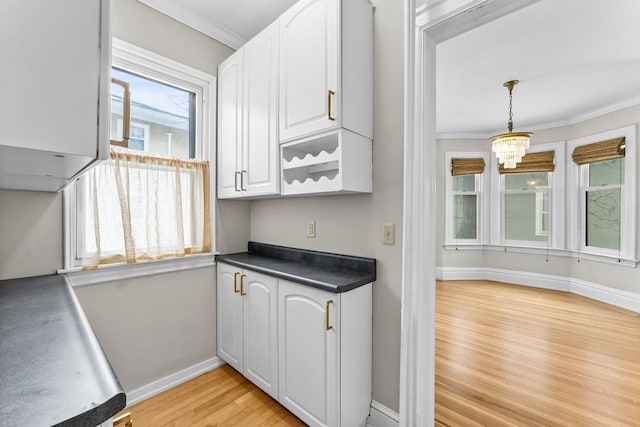 kitchen with pendant lighting, white cabinets, a notable chandelier, light hardwood / wood-style flooring, and crown molding