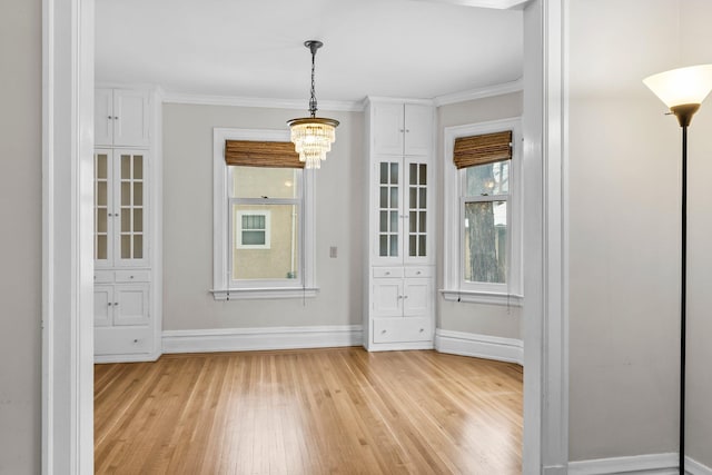 unfurnished dining area with light hardwood / wood-style floors, ornamental molding, and a chandelier