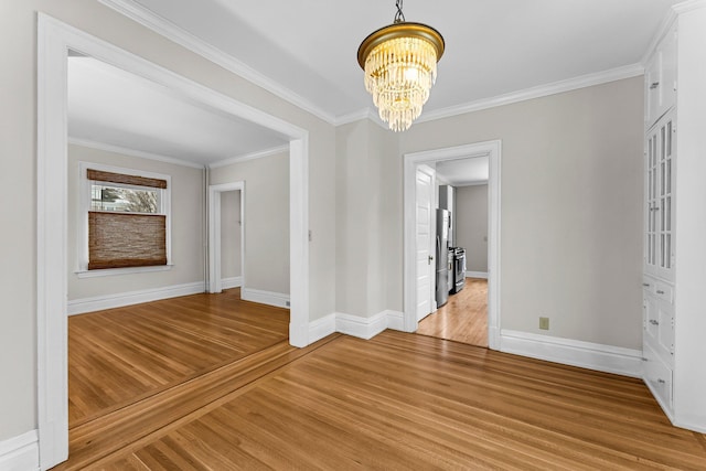 unfurnished dining area with a chandelier, crown molding, and light hardwood / wood-style floors