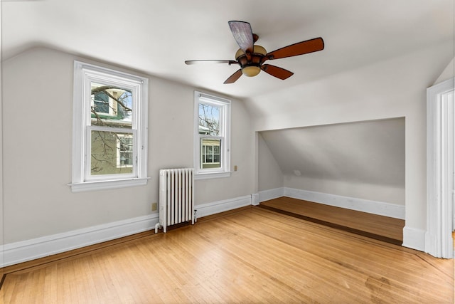 additional living space featuring light wood-type flooring, ceiling fan, radiator heating unit, and lofted ceiling