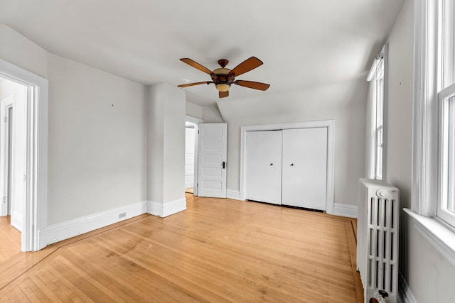 interior space with ceiling fan, radiator, light hardwood / wood-style floors, a closet, and lofted ceiling