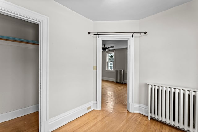 interior space with wood-type flooring, radiator heating unit, and a closet