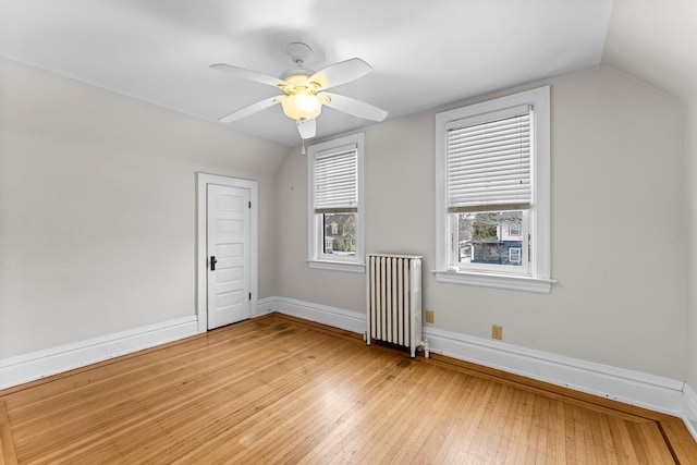 additional living space with ceiling fan, radiator, lofted ceiling, and light wood-type flooring