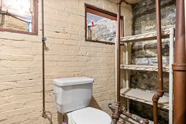 bathroom with toilet and brick wall