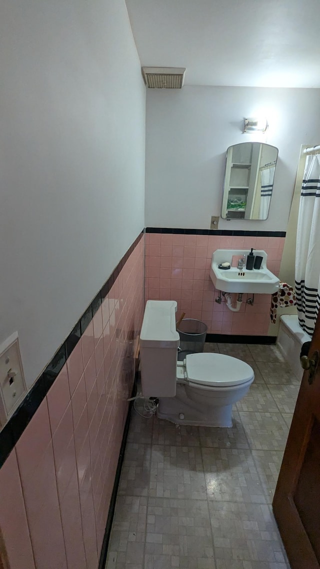 bathroom featuring toilet, tile walls, tile patterned floors, and sink