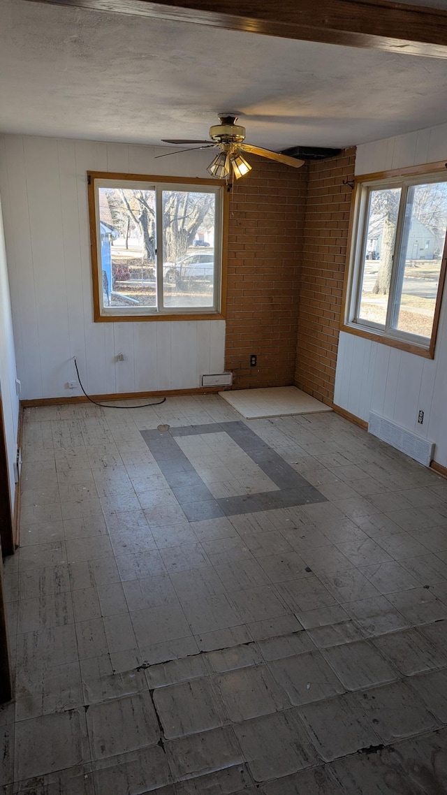 unfurnished room with ceiling fan, brick wall, and light hardwood / wood-style flooring