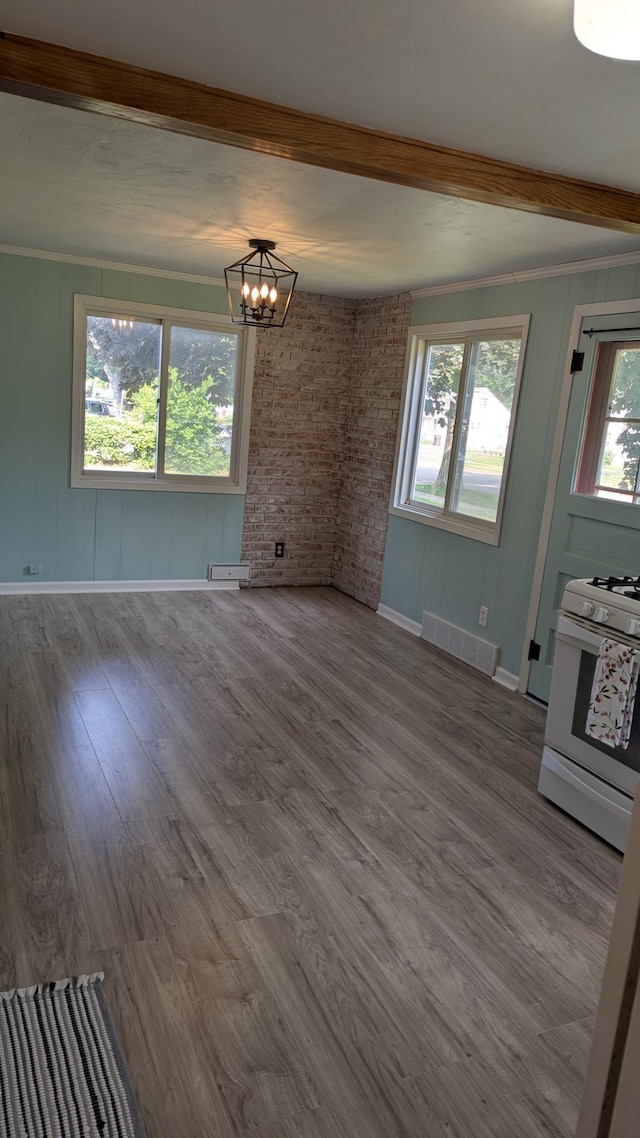 2114 5th Ave NE, Austin, MN 55912 - unfurnished living room featuring a chandelier, beamed ceiling, baseboards, wood finished floors, and crown molding