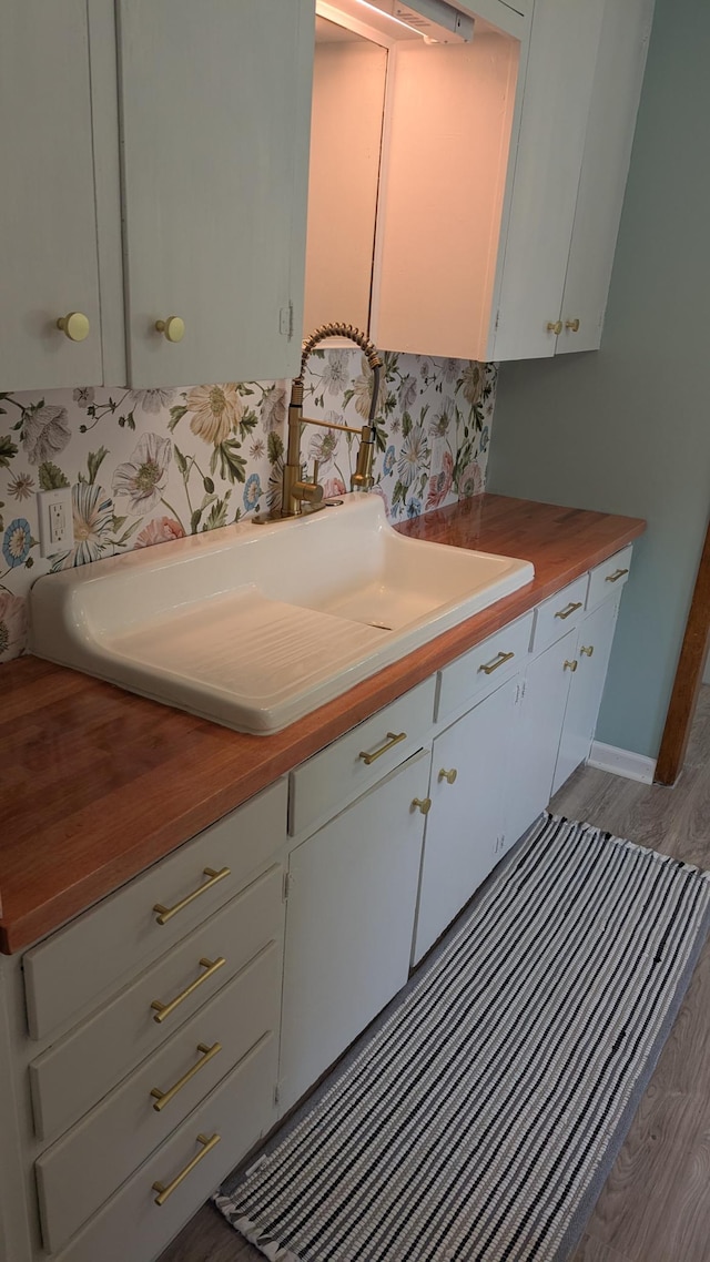 2114 5th Ave NE, Austin, MN 55912 - kitchen with wood finished floors, wood counters, a sink, and white cabinetry