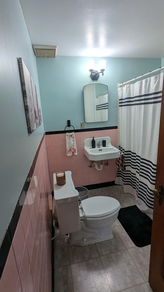2114 5th Ave NE, Austin, MN 55912 - bathroom featuring tile walls, toilet, a sink, a wainscoted wall, and a shower with curtain