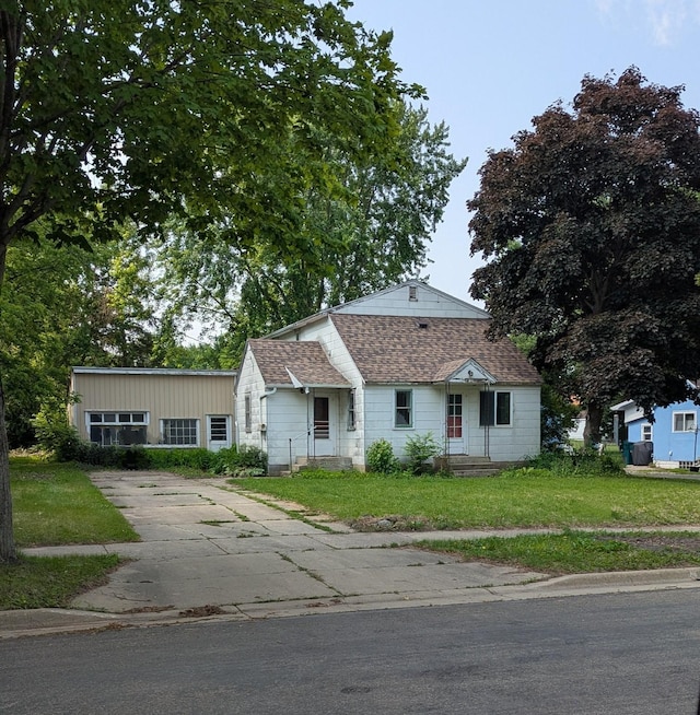 2114 5th Ave NE, Austin, MN 55912 - view of front of house featuring roof with shingles, a front yard, and driveway