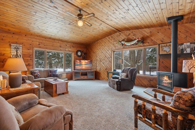 living room with wood walls, wood ceiling, vaulted ceiling, a wood stove, and carpet flooring