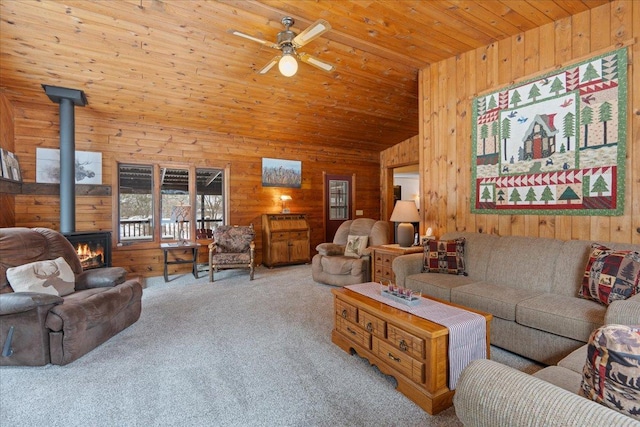 living room with light colored carpet, wooden ceiling, wooden walls, and a wood stove