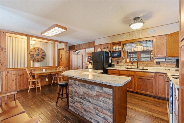 kitchen with dark wood-type flooring, white electric range, sink, black refrigerator, and a kitchen breakfast bar