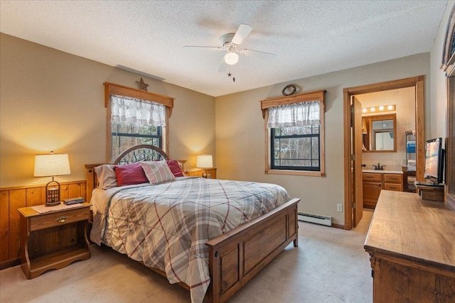 carpeted bedroom with multiple windows, a textured ceiling, baseboard heating, and ensuite bath