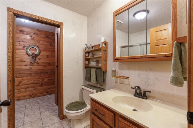 bathroom featuring tile walls, tile patterned flooring, vanity, toilet, and a textured ceiling