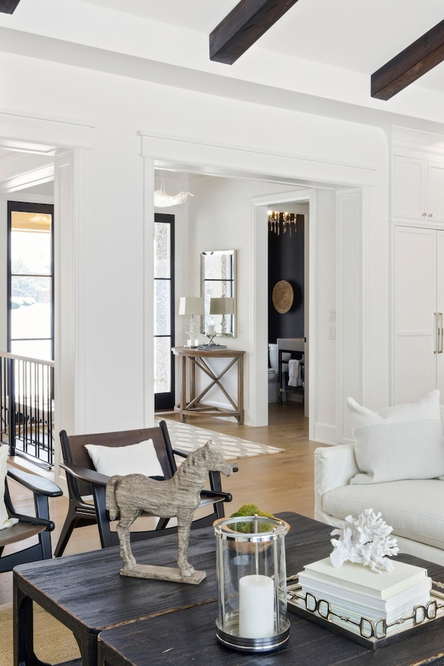 living room with a chandelier, beam ceiling, and hardwood / wood-style flooring