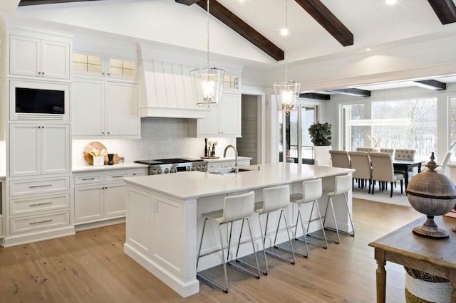 kitchen with a center island with sink, stove, white cabinetry, and sink