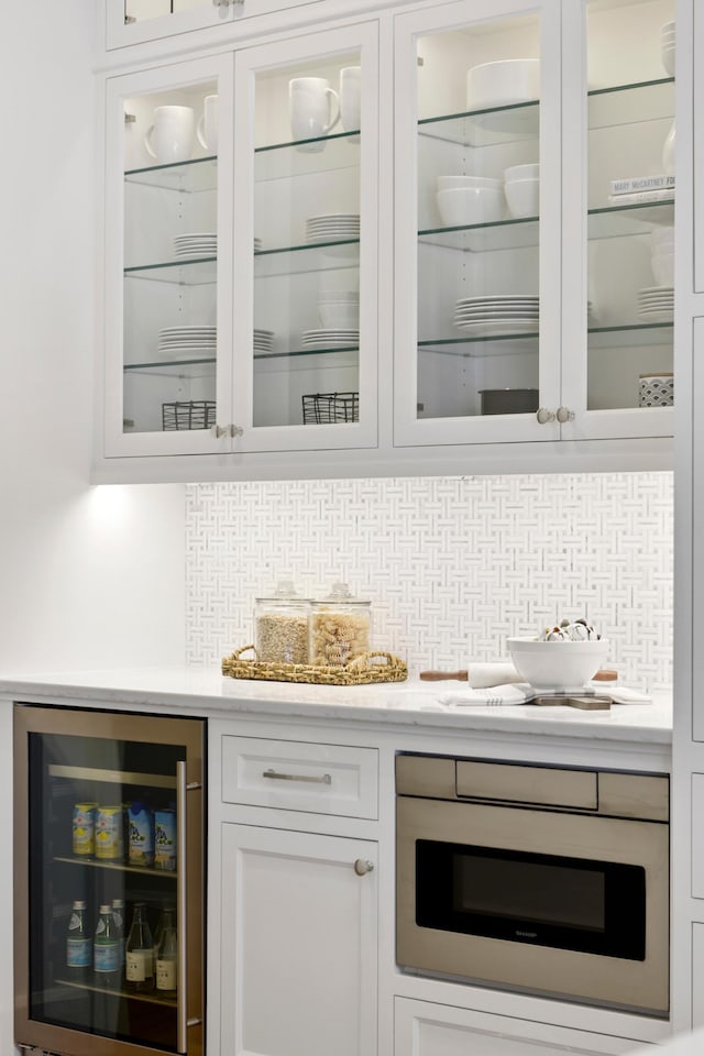 bar featuring oven, white cabinetry, backsplash, and wine cooler