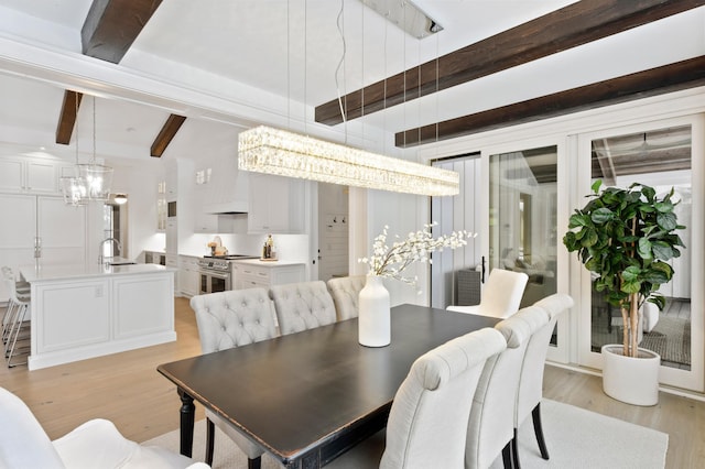 dining area featuring beam ceiling, light hardwood / wood-style flooring, and sink