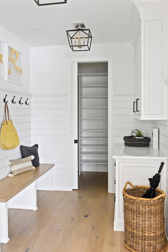 mudroom featuring light wood-type flooring and a chandelier