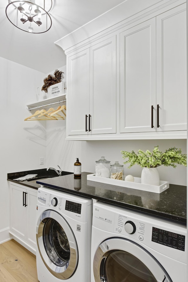 laundry room featuring cabinets, light hardwood / wood-style floors, and washing machine and clothes dryer